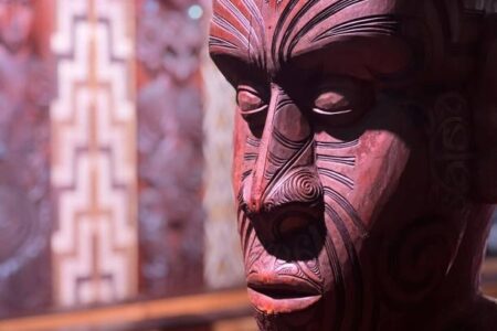 Nahaufnahme einer geschnitzten Māori-Figur mit markanten Gesichtsmotiven