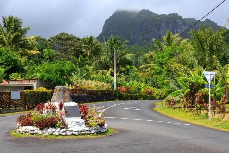 Tropische Straße mit Palmen und bewachsenem Berg auf Rarotonga